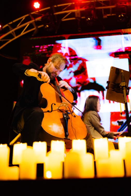 Wesley Skinner playing cello behind a row of candles
