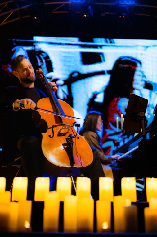 Cellist deep in performance, candles in the foreground